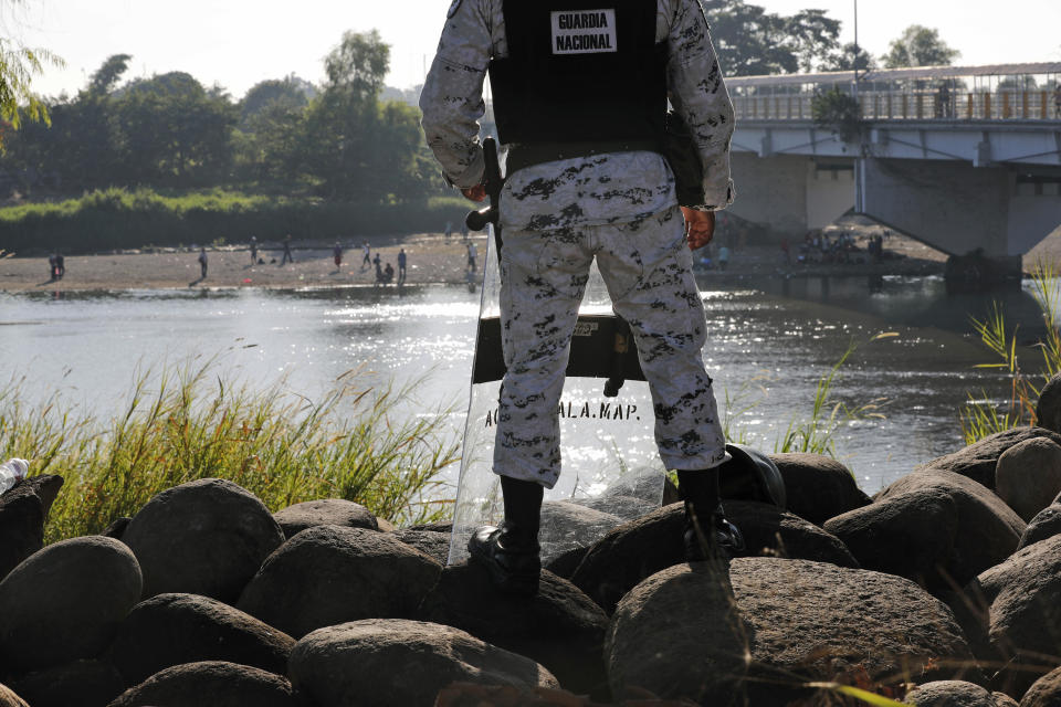 Mexican National Guardsmen look at the bridge spanning the Suchiate River in Ciudad Hidalgo, on the Mexican border with Guatemala, near Ciudad Hidalgo, Mexico, Sunday, Jan. 19, 2020. Mexican authorities have closed a border entry point in southern Mexico after thousands of Central American migrants tried to push across a bridge between Mexico and Guatemala. (AP Photo/Marco Ugarte)