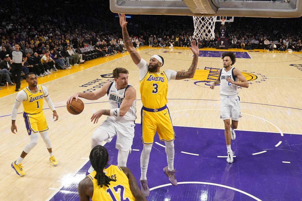 Dallas Mavericks guard Luka Doncic, second from left, makes a behind-the-back pass to center Dereck Lively II (2, past Los Angeles Lakers forward Anthony Davis (3) during the first half of an NBA basketball game Wednesday, Nov. 22, 2023, in Los Angeles. (AP Photo/Marcio Jose Sanchez)