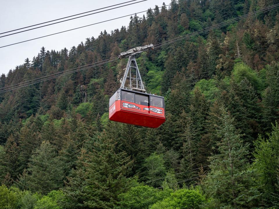 Red tram on wires going up tree-covered mountain in Alaska