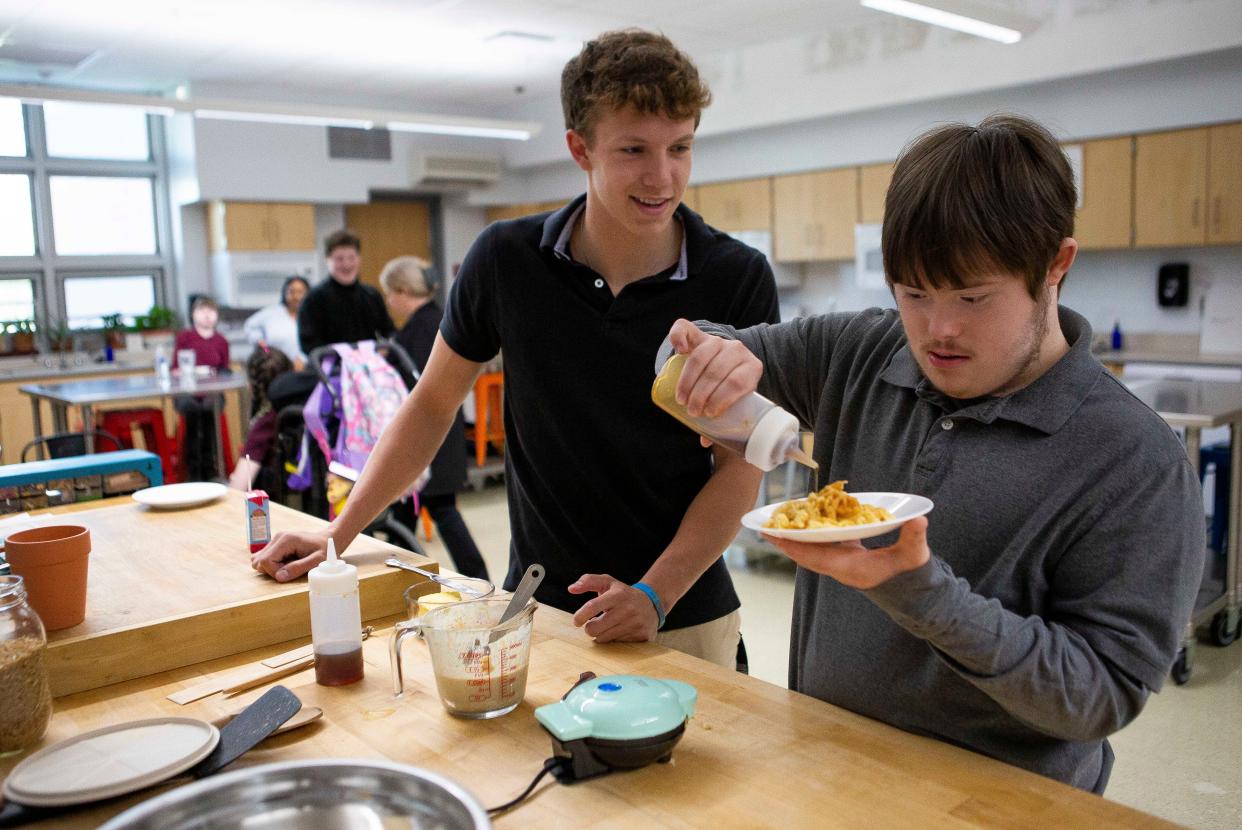 Newark High School senior Noah Dagois (left) watches as his good friend Leland Mummey, 16, pours syrup on the waffle he and Noah made together in Leona Vrbanac's Life Skills joint class between Friends (special needs students and their mentors) at the high school on May 17, 2022. Dagois and Mummey met in the seventh grade and have been close friends ever since.