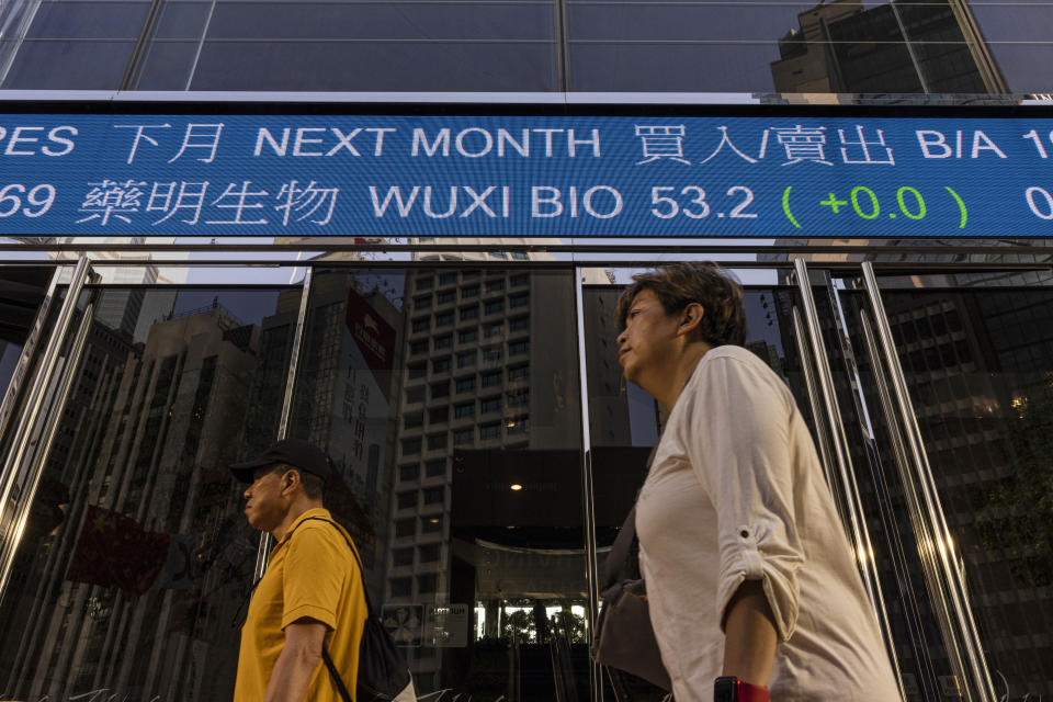 People walk past the Hong Kong Stock Exchange electronic screen in Hong Kong on Friday, March 10, 2023. Asian stock markets followed Wall Street lower Friday ahead of an update on U.S. employment amid worries about possible further interest rate hikes. (AP Photo/Louise Delmotte)