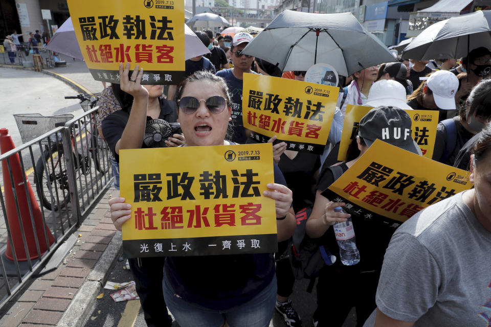 Protesters hold up words that read: "Strict enforcing of law against smugglers of grey goods" in Hong Kong Saturday, July 13, 2019. Several thousand people are marching in Hong Kong against traders from mainland China in what is fast becoming a summer of unrest in the semi-autonomous Chinese territory. (AP Photo/Kin Cheung)