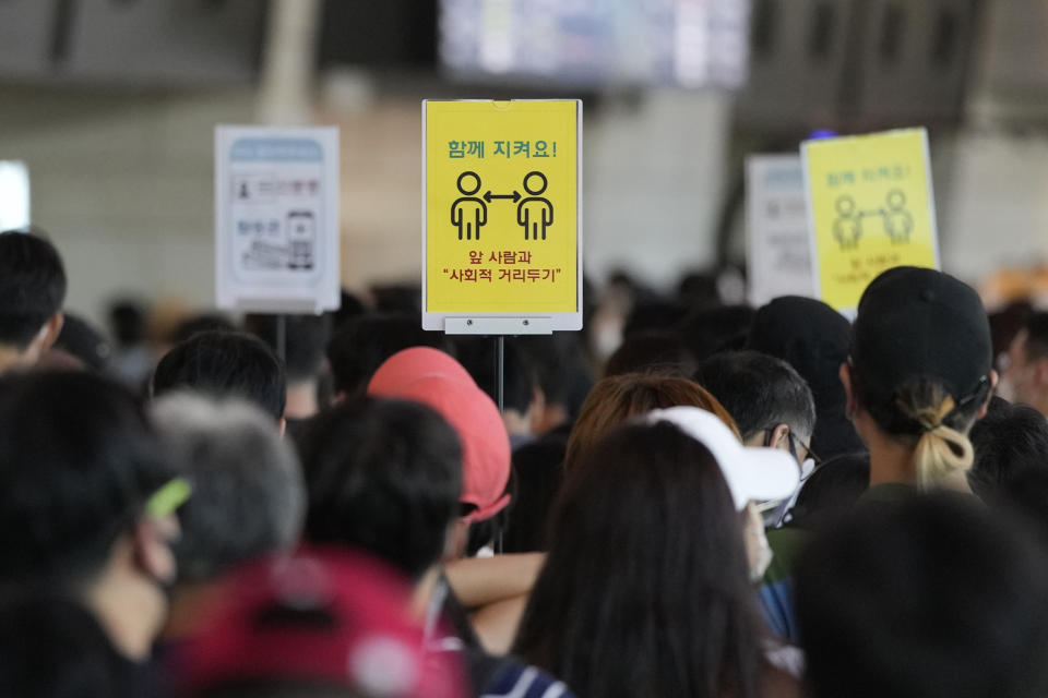 Signs for social distancing are seen as passengers wait to board planes ahead of the upcoming Chuseok holiday, the Korean version of Thanksgiving Day, which falls on Sept. 21, at the domestic flight terminal of Gimpo airport in Seoul, South Korea, Saturday, Sept. 18, 2021. The signs read: "Keep together." (AP Photo/Ahn Young-joon)