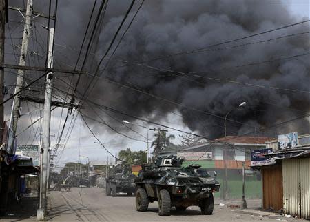 Government soldiers inside armoured vehicles take part in a firefight with Muslim rebels from Moro National Liberation Front (MNLF) amidst smoke from burning houses in a residential district in Zamboanga city in southern Philippines September 12, 2013. REUTERS/Erik De Castro