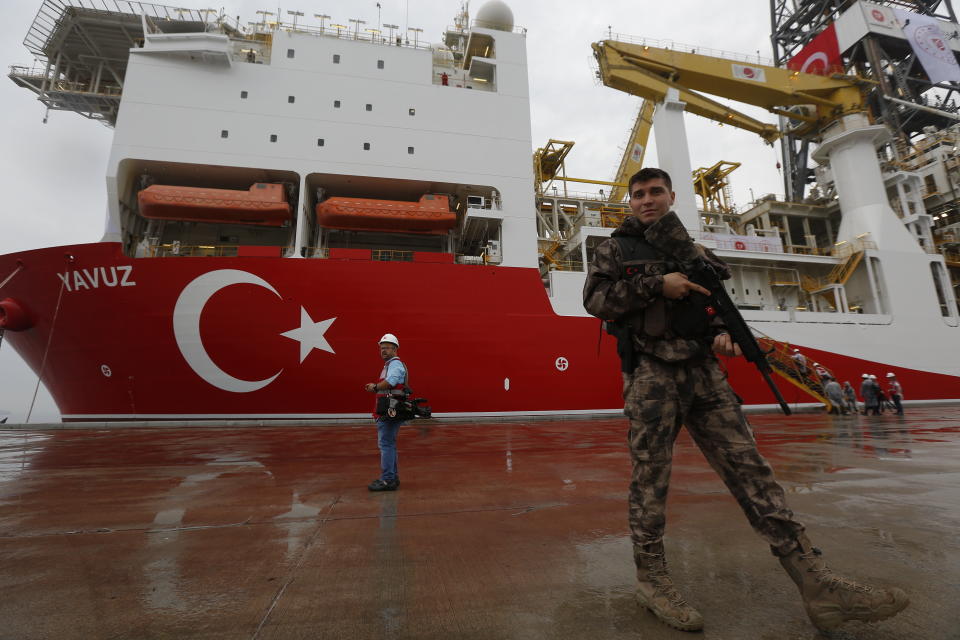 FILE - In this Thursday, June 20, 2019 file photo, a Turkish police officer patrols the dock, backdropped by the drilling ship 'Yavuz' to be dispatched to the Mediterranean, at the port of Dilovasi, outside Istanbul. The leaders of Greece, Israel and Cyprus are set to sign a deal Thursday Jan. 2, 2020, for a 1,900-kilometer (1,300-mile) undersea pipeline that will carry gas from new offshore deposits in the southeastern Mediterranean to continental Europe. (AP Photo/Lefteris Pitarakis, File)