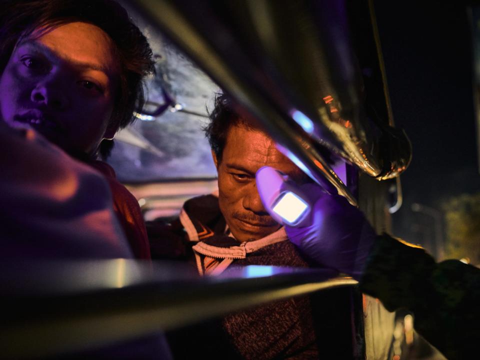 Commuters on their vehicles sit in traffic as they pass through a police checkpoint to have their temperatures taken, in Quezon City, Philippines on March 15.