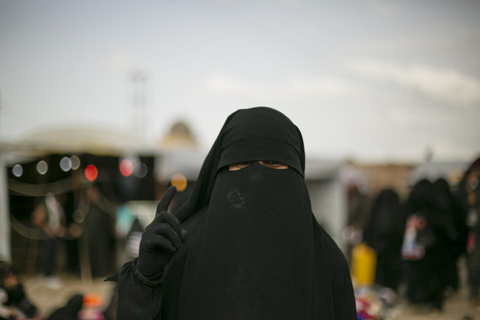 FILE - In this March 31, 2019, file, photo, a woman gestures for a portrait at al-Hol camp, which holds families of Islamic State members, in Hasakeh province, Syria. Security conditions in the al-Hol camp that is home to tens of thousands of wives and children of Islamic State group fighters has been bad for the past months and will likely get worse now that Turkey is on the offensive in northern Syria. The camp that is home to more than 70,000 has witnessed crimes carried out by IS women against residents whom they consider apostates.(AP Photo/Maya Alleruzzo, File)