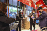 A worker dispenses hand sanitizer to shoppers at the entrance of a supermarket in Wuhan in central China's Hubei province, Saturday, Jan. 25, 2020. The virus-hit Chinese city of Wuhan, already on lockdown, banned most vehicle use downtown and Hong Kong said it would close schools for two weeks as authorities scrambled Saturday to stop the spread of an illness that is known to have infected more than 1,200 people and killed 41, according to officials. (Chinatopix via AP)