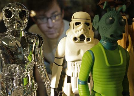 A employee poses with Star Wars figures at the Forbidden Planet memorabilia and comic store in London May 11, 2013. REUTERS/Luke MacGregor