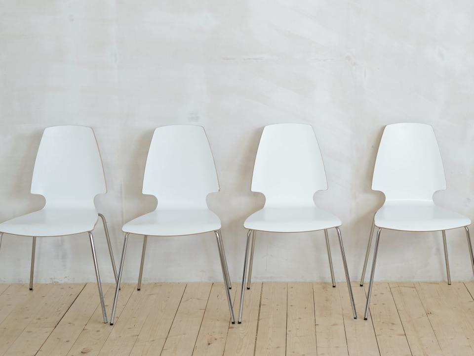 Row of white chairs near wall