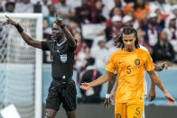 Referee Bakary Gassama gestures before consulting the VAR next to Nathan Ake of the Netherlands during the World Cup group A soccer match between the Netherlands and Qatar, at the Al Bayt Stadium in Al Khor , Qatar, Tuesday, Nov. 29, 2022. (AP Photo/Moises Castillo)