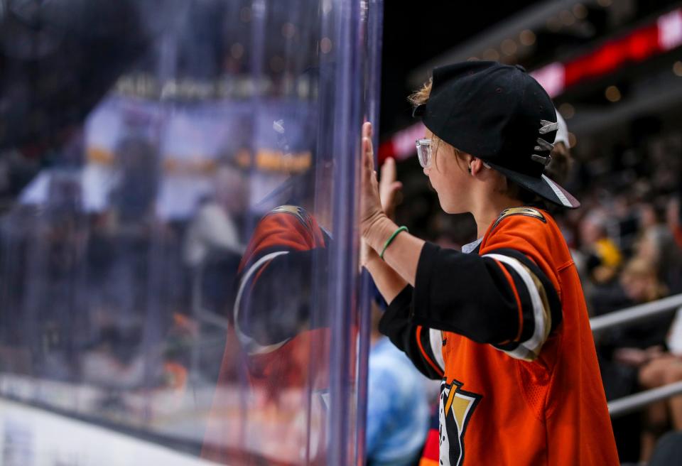 A young Anaheim Ducks fan bangs on the glass to cheer for the team during the second period of their exhibition game at Acrisure Arena in Palm Desert, Calif., Sunday, Oct. 1, 2023.