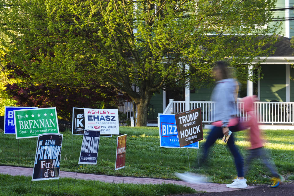 A voter and child walk past campaign signs posted outside of a polling site in Doylestown, Pa., Tuesday, April 23, 2024. (AP Photo/Matt Rourke)