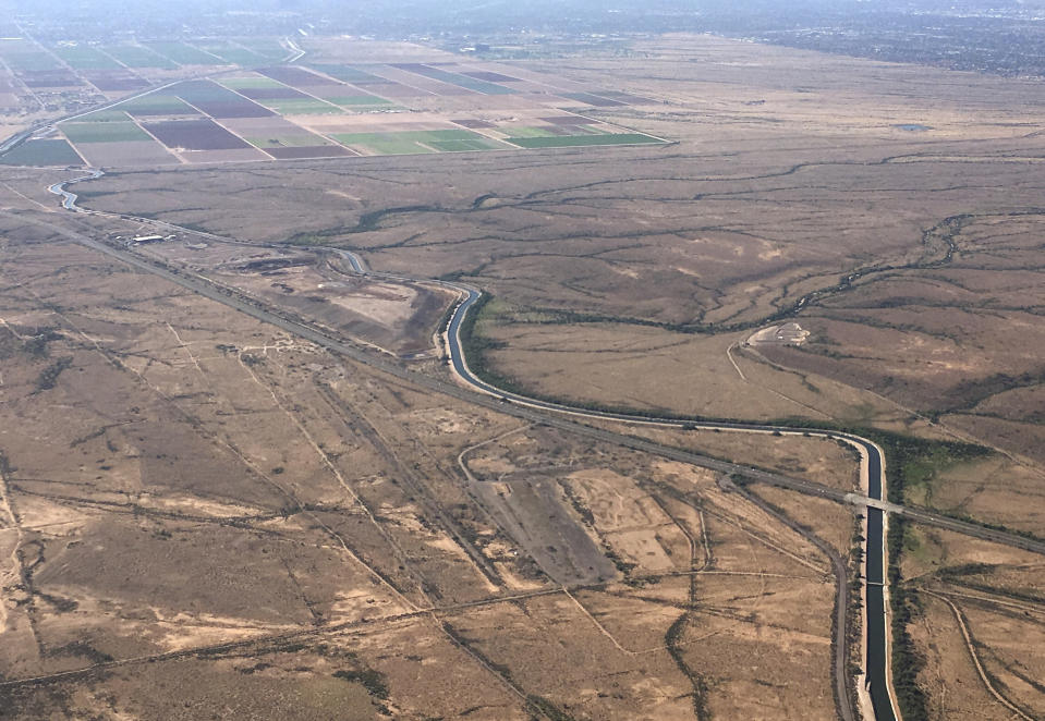 FILE - In this Oct. 8, 2019, file photo, the Central Arizona Project canal runs through rural desert near Phoenix. Water officials in Arizona say they are prepared to lose about one-fifth of the water the state gets from the Colorado River in what could be the first federally declared shortage in the river that supplies millions of people in the U.S. West and Mexico. The voluntary and mandatory Tier 1 cuts mean Arizona will lose 18% of its Colorado River supply, or 512,000 acre-feet of water. The amount represents 30% of the water that goes to the Central Arizona Project, which manages the canal system and had made excess water available for farmers. (AP Photo/Ross D. Franklin, File)