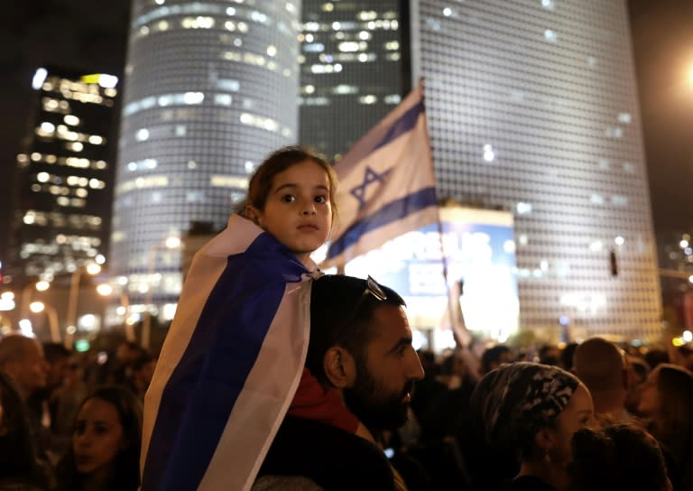 A young Israeli wears a national flag as fellow Israelis protest against a recent cease fire with the Hamas movement, in the coastal city of Tel Aviv on November 15, 2018