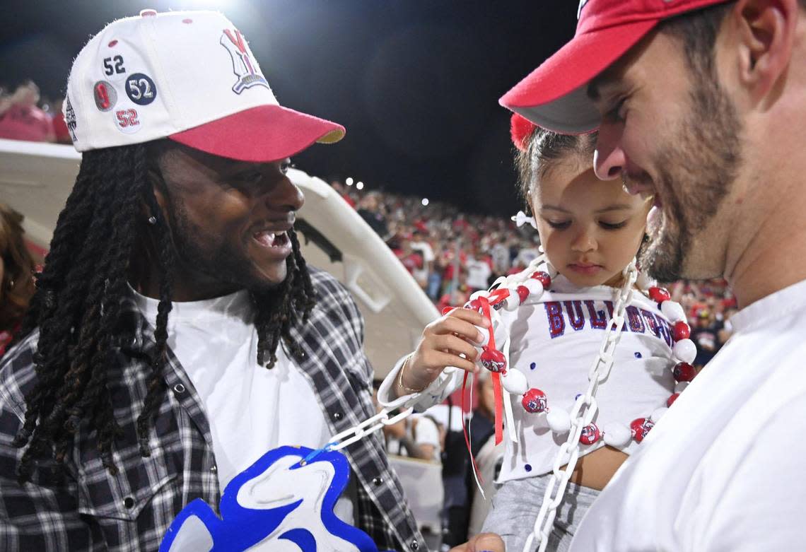 Davante Adams, left, laughs as Derek Carr, right, holds his daughter Saturday, Oct. 15, 2022 in Fresno.