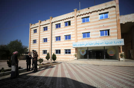 People stand near the civil administration building of Manbij city, Syria December 29, 2018. Picture taken December 29, 2018. REUTERS/Rodi Said