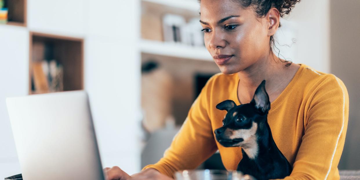 woman and dog typing on laptop computer with coffee at home