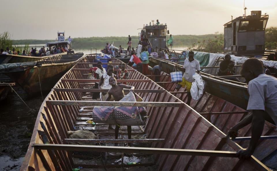 In this photo taken Thursday, Jan. 2, 2014, displaced people arrive with what belongings they had time to gather by river barge from Bor, some of the thousands who fled the recent fighting between government and rebel forces in Bor by boat across the White Nile, in the town of Awerial, South Sudan. (AP Photo/Ben Curtis)