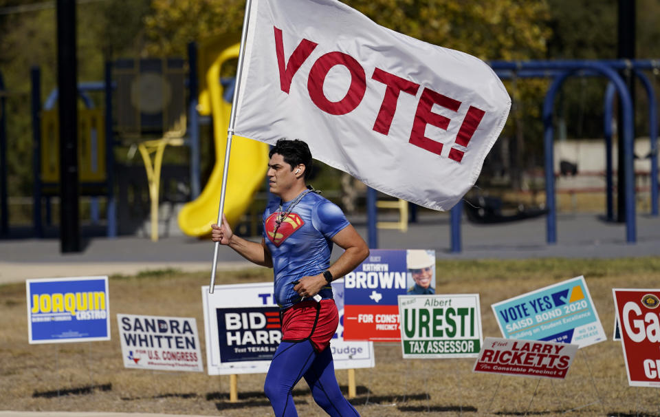 Un corredor lleva un bandera que dice ¡Vota! frente a un centro de votación en San Antono, Texas. (AP Photo/Eric Gay)