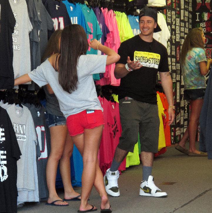 This June 8, 2012 photo shows "Jersey Shore" cast member Vinny Guadagnino chatting up two girls inside a T-shirt shop on the Seaside Heights, N.J. boardwalk while filming an episode of the MTV reality show. Cast members Deena Cortese and Ronnie Ortiz-Magro have found themselves in legal trouble during filming of the series 6th season this year. (AP Photo/Wayne Parry)