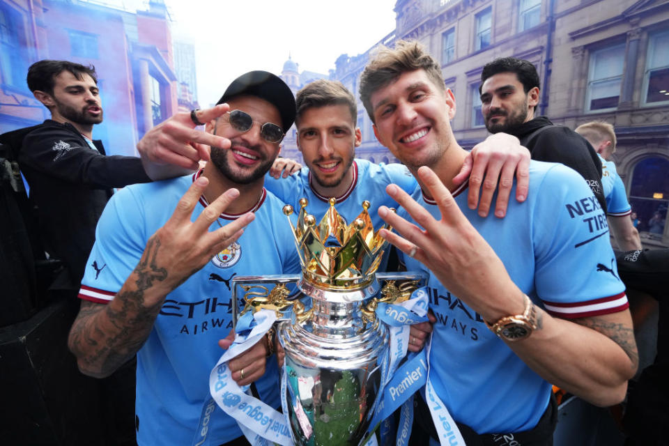 Kyle Walker, Ruben Dias and John Stones of Manchester City pose for a photo with the Premier League trophy during the Manchester City FC Victory Parade on May 23, 2022 in Manchester, England.