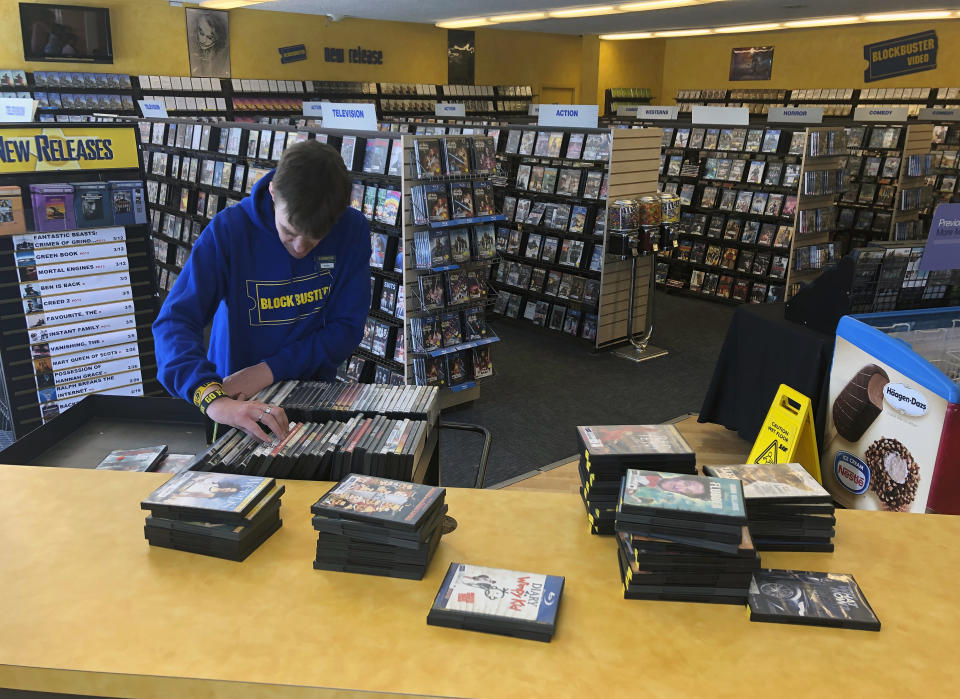 FILE - In this March 12, 2019, file photo employee Ryan Larrew alphabetizes returned movies before re-shelving them at the last Blockbuster store on the planet in Bend, Ore. The new Netflix movie called The Last Blockbuster that began airing March 15, 2021, is generating interest in the store, which became the last Blockbuster location on Earth when a location in Perth, Australia shut its doors in 2019. (AP Photo/Gillian Flaccus, File)