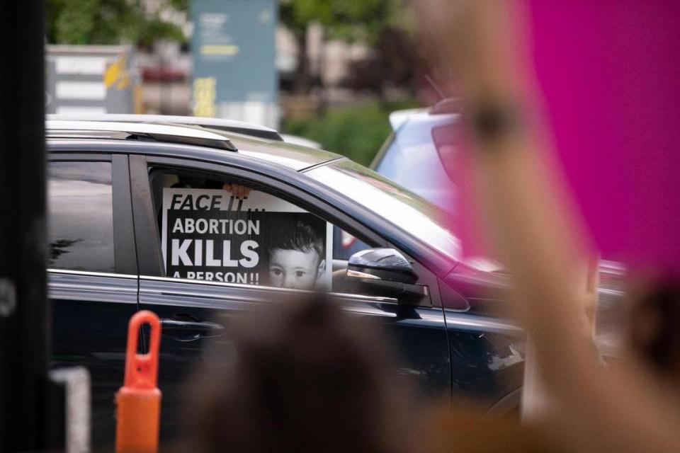 A driver passes the Rise Up 4 Abortion Rights protest holding a sign outside the courthouse in downtown Lexington, Ky., Saturday, May 14, 2022.