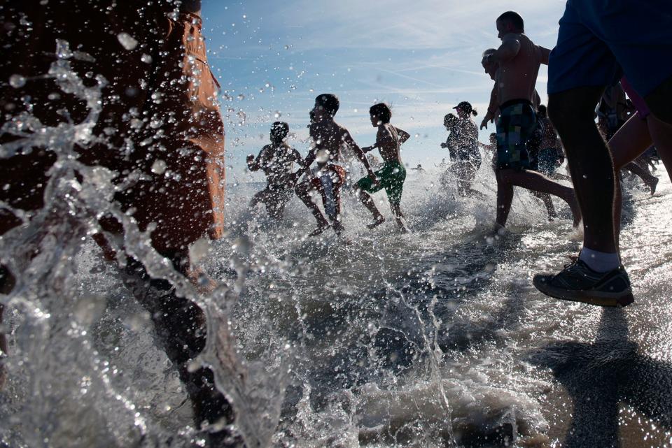 Crowds of people rush into the ocean as the 19th annual Leo Brady Exercise like the Eskimos Plunge ensues Thursday, Jan. 1 in Bethany Beach.
