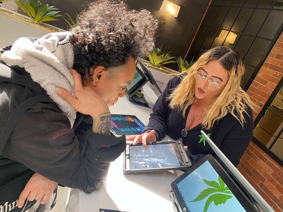 Mother Earth Wellness "budtender" Tori Chipman helps a customer on an iPad.