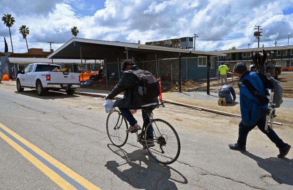 A bicyclist and a pedestrian pass by the Villa Motel on Parkway Drive in central Fresno, where renovation work is taking place on Thursday, March 30, 2023. The motel is one of five in the immediate area that have been converted to serve as emergency shelters for the homeless.