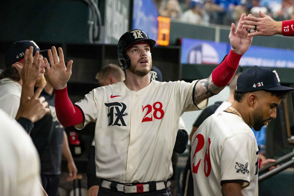 Texas Rangers' Jonah Heim (28) high-fives teammates after scoring a run in the bottom of the second inning in a baseball game against the Cleveland Guardians in Arlington, Texas, Saturday, July 15, 2023. (AP Photo/Emil T. Lippe)