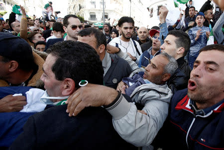 People evacuate a man after police sprayed tear gas during a protest against the appointment of interim president Abdelkader Bensalah demanding radical changes to the political system, in Algiers, Algeria April 10, 2019. REUTERS/Ramzi Boudina