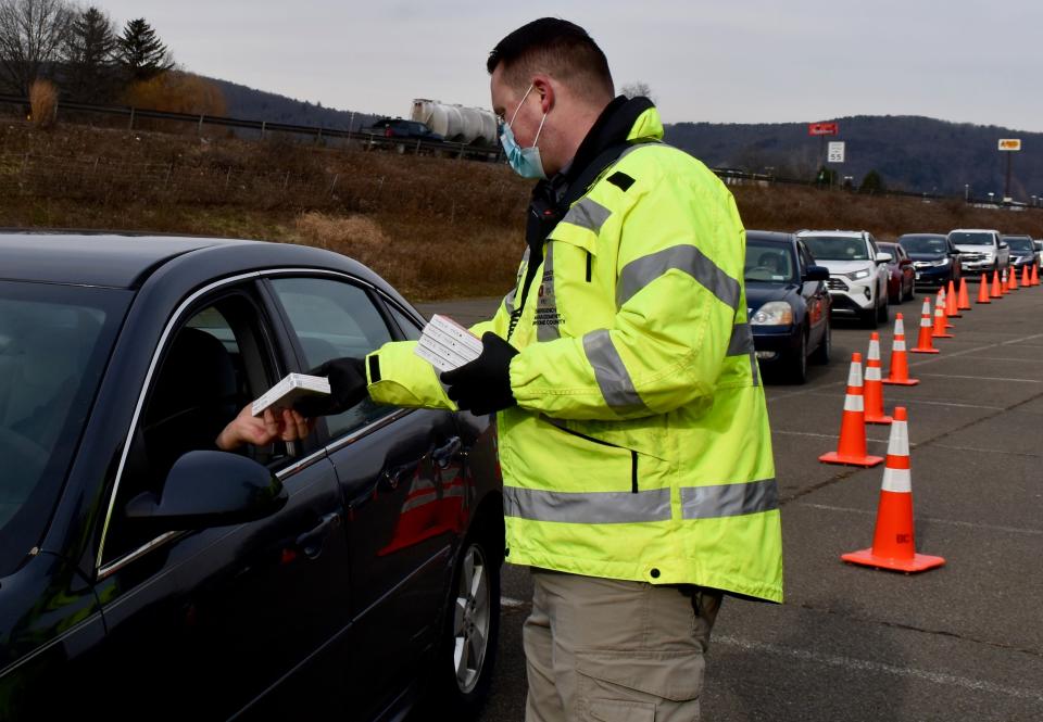 Matt Sitek, of the Broome County Office of Emergency Services, distributes two packs of at-home rapid COVID-19 tests to a line of cars at Otsiningo Park in the Town of Dickinson on Wednesday, Jan. 5.