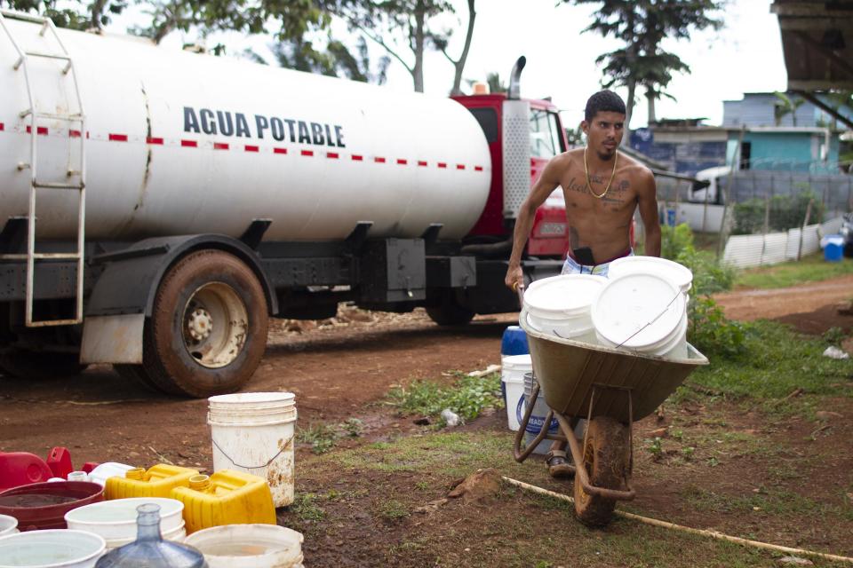 Joven cargando cubos de agua tras llenarlos en cisterna