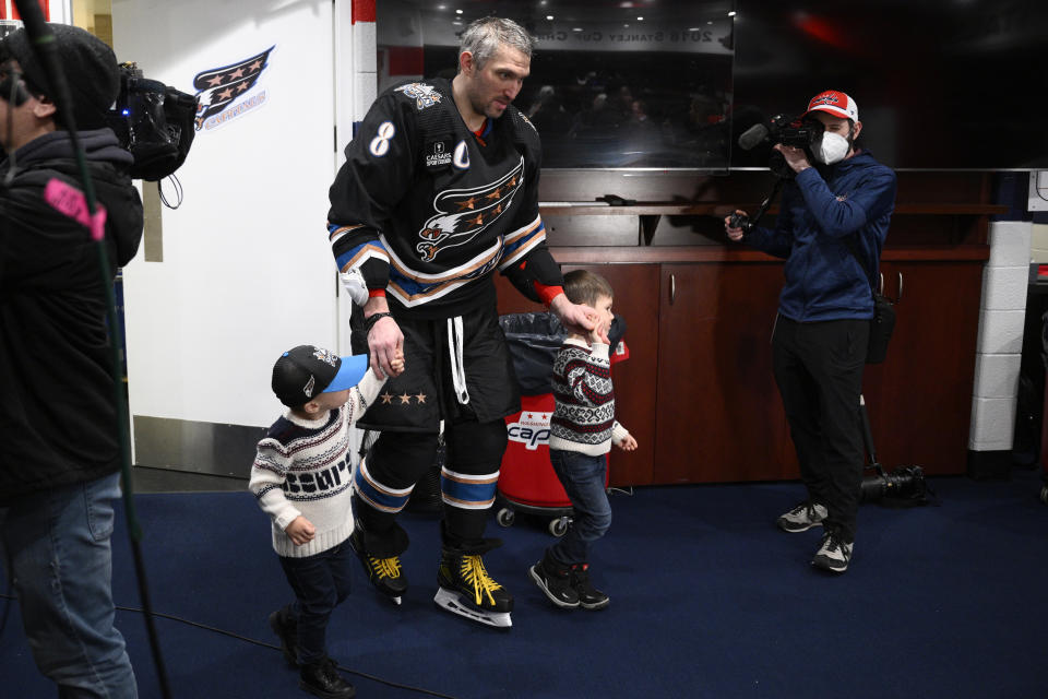 Washington Capitals left wing Alex Ovechkin (8) walks with his sons Ilya, left, and Sergei, right, in the locker room after an NHL hockey game against the Winnipeg Jets, Friday, Dec. 23, 2022, in Washington. (AP Photo/Nick Wass)