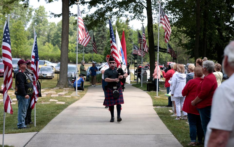 Bagpiper David Wurtz with the Metro Detroit Police and Fire Pipes and Drums leads a procession to start the memorial service for Colt and Lucky6, two Michigan military war dogs who were laid to rest at the Michigan War Dog Memorial in South Lyon on June 17, 2023.