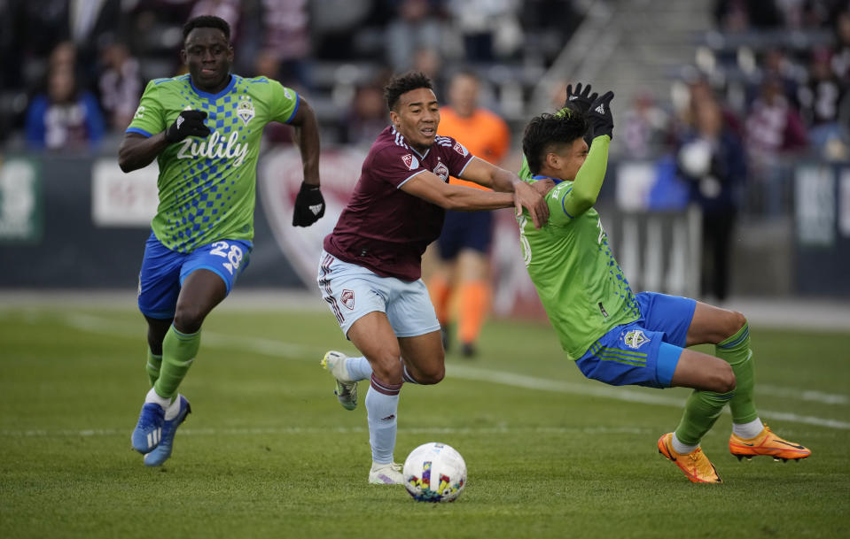 Colorado Rapids forward Jonathan Lewis, center, pursues the ball with Seattle Sounders defenders Yeimar Gómez, left, and Xavier Arreaga in the second half of an MLS soccer match, Sunday, May 22 2022, in Commerce City, Colo. (AP Photo/David Zalubowski)