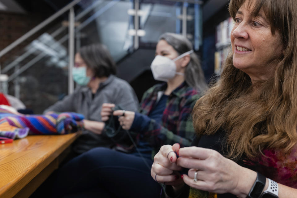 In this photo provided by Edward Boches, Roz Switalski, right, knits a blanket in a knitting circle with other volunteers, Jan. 8, 2023, in Brookline, Mass. The Welcome Blankets will be donated to agencies helping immigrants who recently arrived in the United States. (Edward Boches via AP)