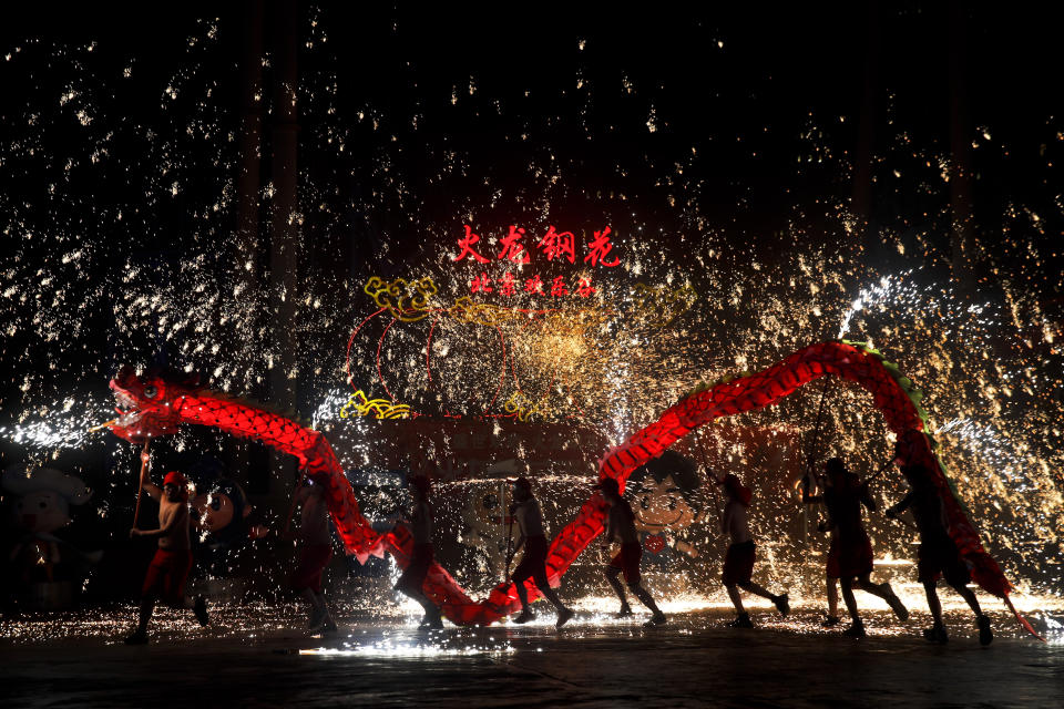 In this Saturday, Feb. 9, 2019, file photo, fire dragon dancers perform under a shower of sparks from molten iron during a temple fair at the Happy Valley amusement park in Beijing. Chinese people are enjoying a weeklong holiday for the Lunar New Year and visiting various temple fairs and carnivals held in the cities around China. (AP Photo/Andy Wong, File)