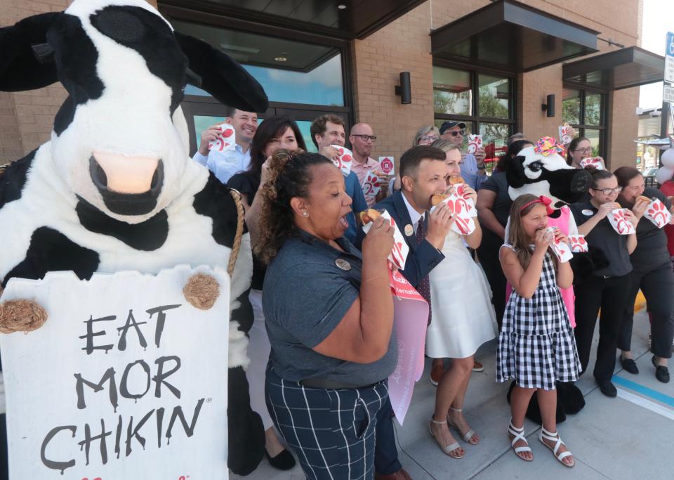 Chris Kirby (center), franchisee of the new Chick-fil-A on International Speedway Boulevard in Daytona Beach, is joined by his wife, Jenna, their kids, family, friends and employees to cut the ribbon to the new restaurant on Thursday and have the first bite of chicken sandwiches.