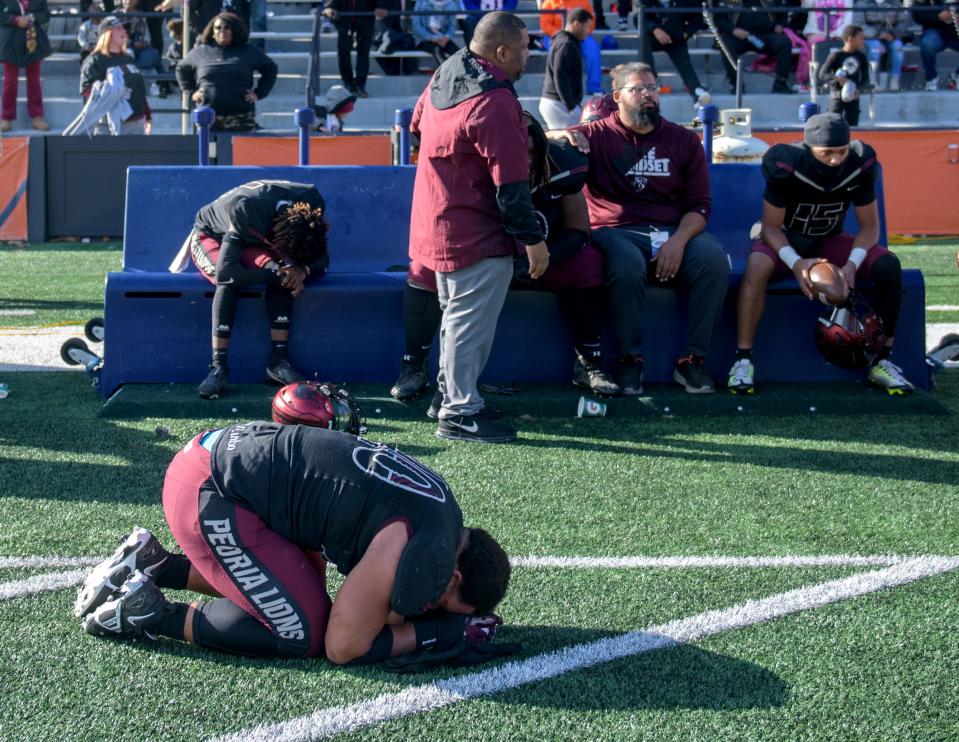 Peoria High's Landon Newby-Holesome, on the turf, and his teammates lament their one-point loss to Nazareth Academy in the Class 5A football state title game Saturday, Nov. 26, 2022 in Champaign. The Lions fell to the Roadrunners 45-44.