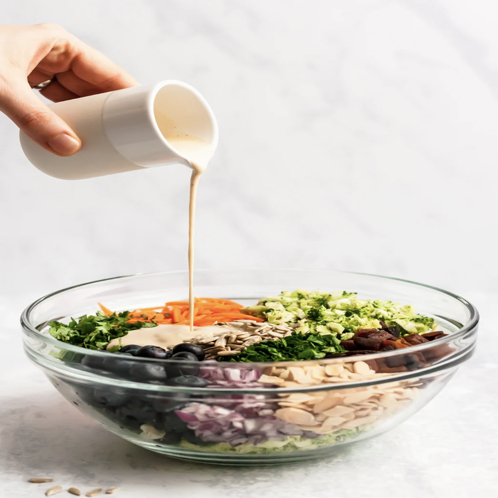 Pouring dressing onto broccoli salad.