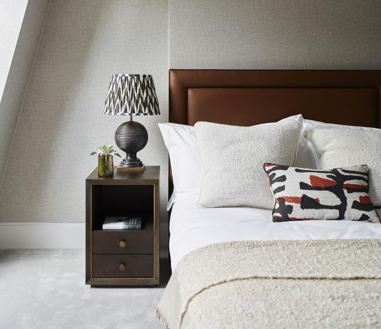  A neutral bedroom with a patterned lampshade and textured cushions and a fluffy throw. 