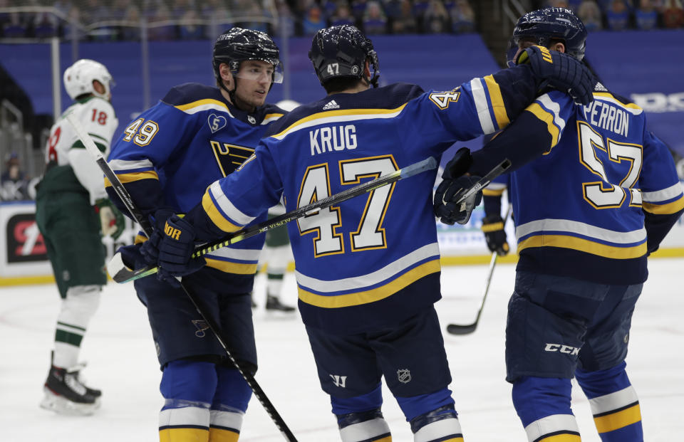 St. Louis Blues' Torey Krug (47) celebrates a goal with teammates Ivan Barbashev (49) and David Perron (57), as Minnesota Wild's Jordan Greenway (18) skates by, in the second period of an NHL hockey game, Wednesday, May 12, 2021 in St. Louis. (AP Photo/Tom Gannam)