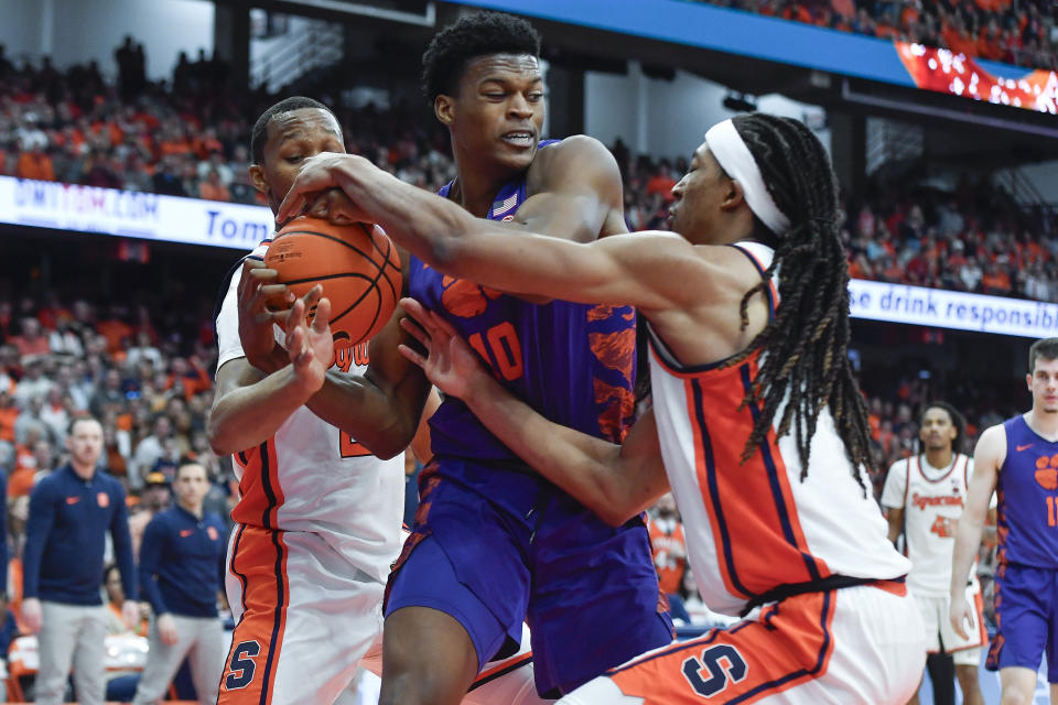 Clemson forward RJ Godfrey, center, fights for a rebound against Syracuse guard Quadir Copeland, left, and forward Maliq Brown during the second half of an NCAA college basketball game in Syracuse, N.Y., Saturday, Feb. 10, 2024. (AP Photo/Adrian Kraus)