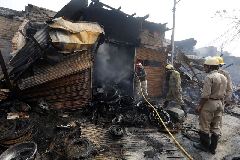 Firefighters douse the burning wreckage of a shop at a tyre market after it was set on fire by a mob in a riot affected area after clashes erupted between people demonstrating for and against a new citizenship law in New Delhi