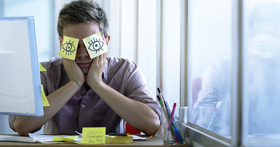 A young employee sleeps in the office hiding with posits in the eyes