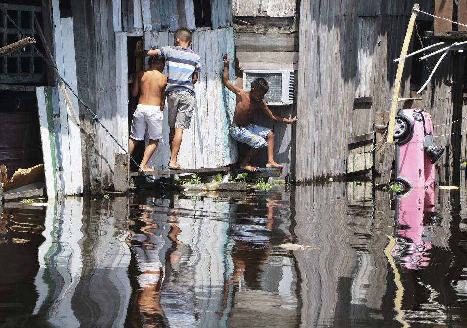 Children play outside a house, surrounded by the floodwaters of the Negro River in Manaus, Brazil, Thursday, May 20, 2021. According to official records taken by the Port of Manaus, the city is facing one of its worse floods in years, with levels not seen since 1902, making it the second-worst flood ever recorded. (AP Photo/Edmar Barros)