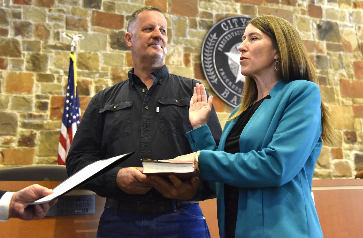 Newly elected Bastrop City Council Member Kerry Fossler takes the oath of office with her husband, Steve Fossler, holding the Bible.